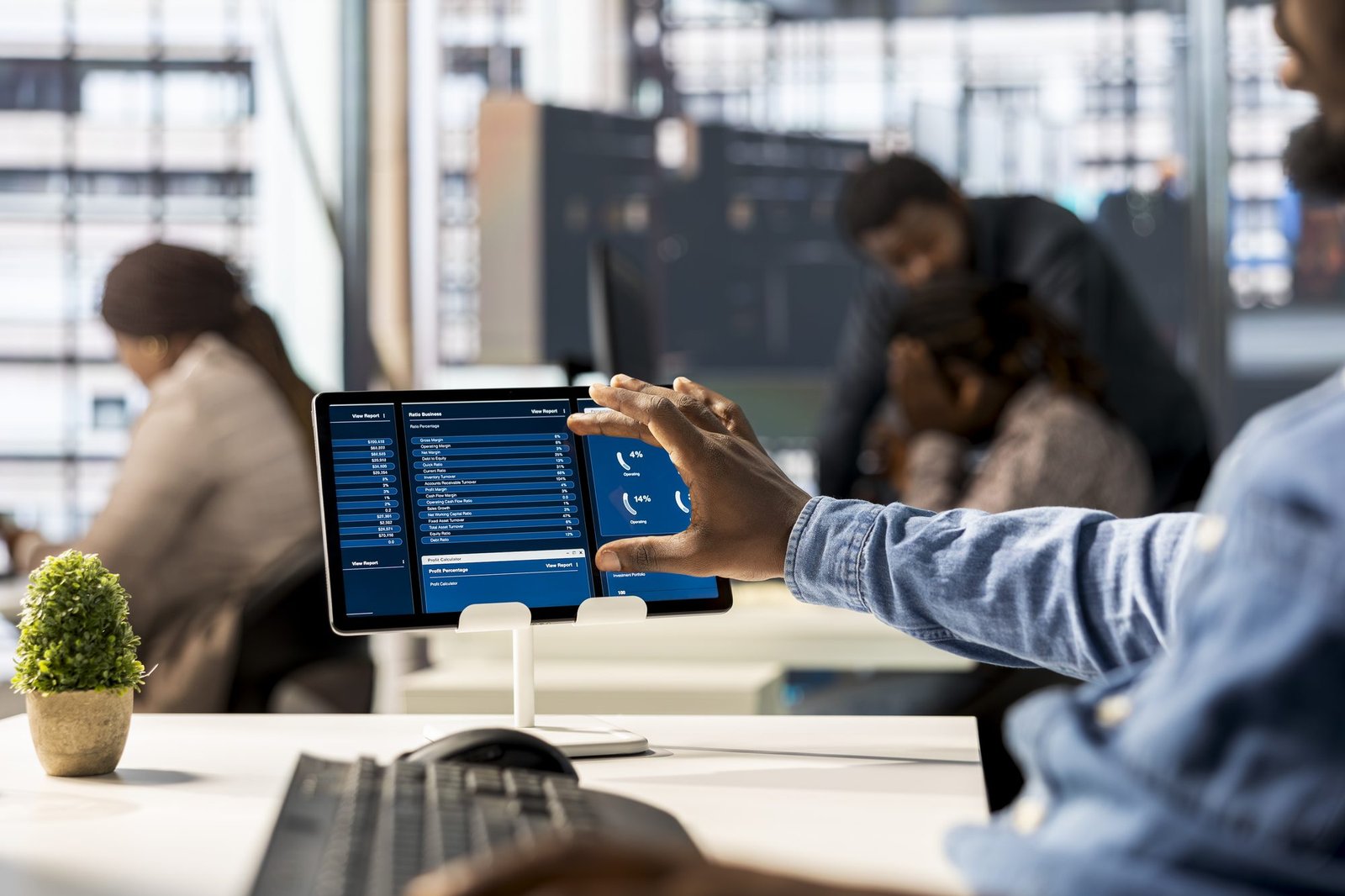 Analista apontando para um tablet com dashboards financeiros em escritório moderno